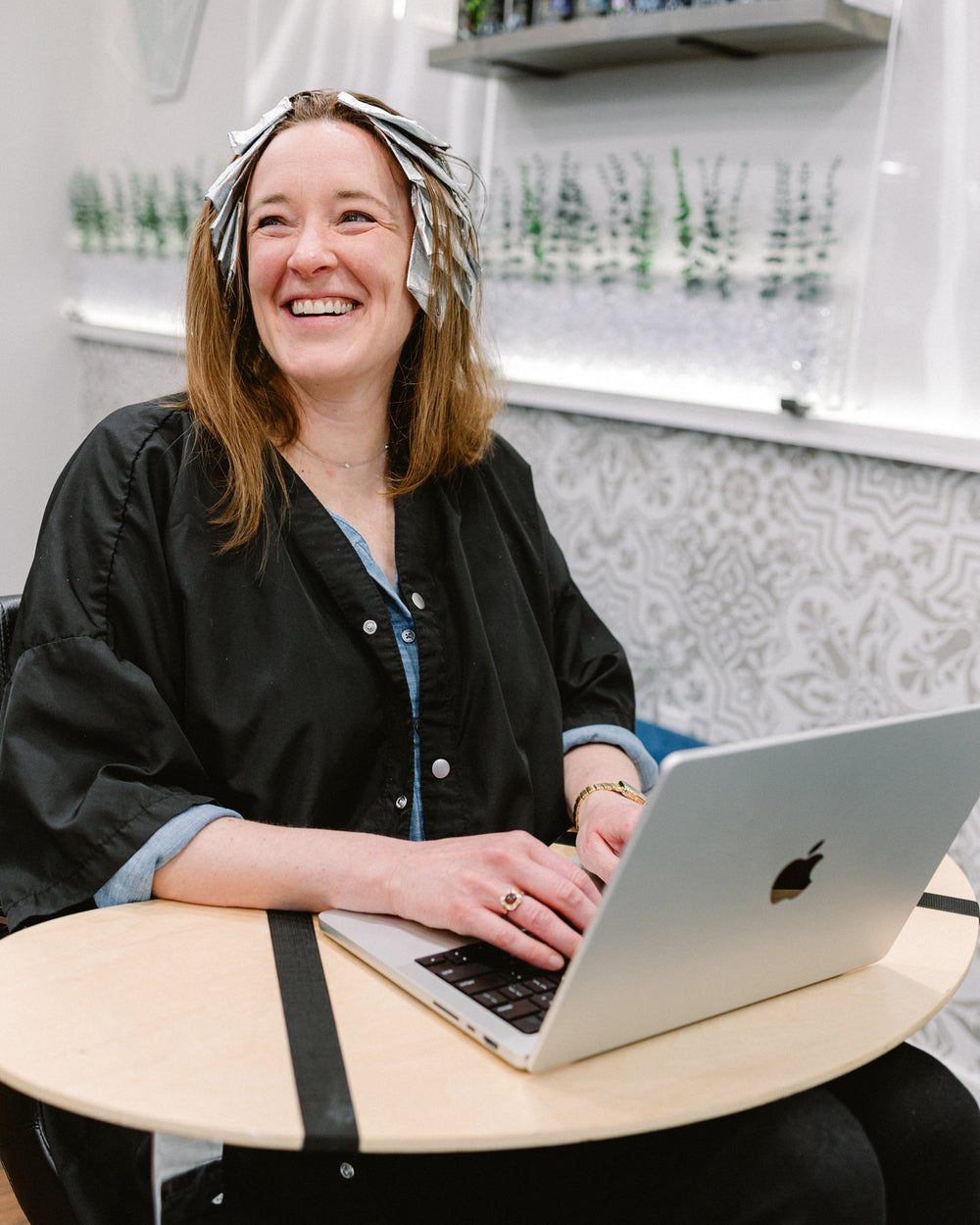 Guest smiling with a laptop during foils at Elevate Salon + Spa, Charlottesville VA