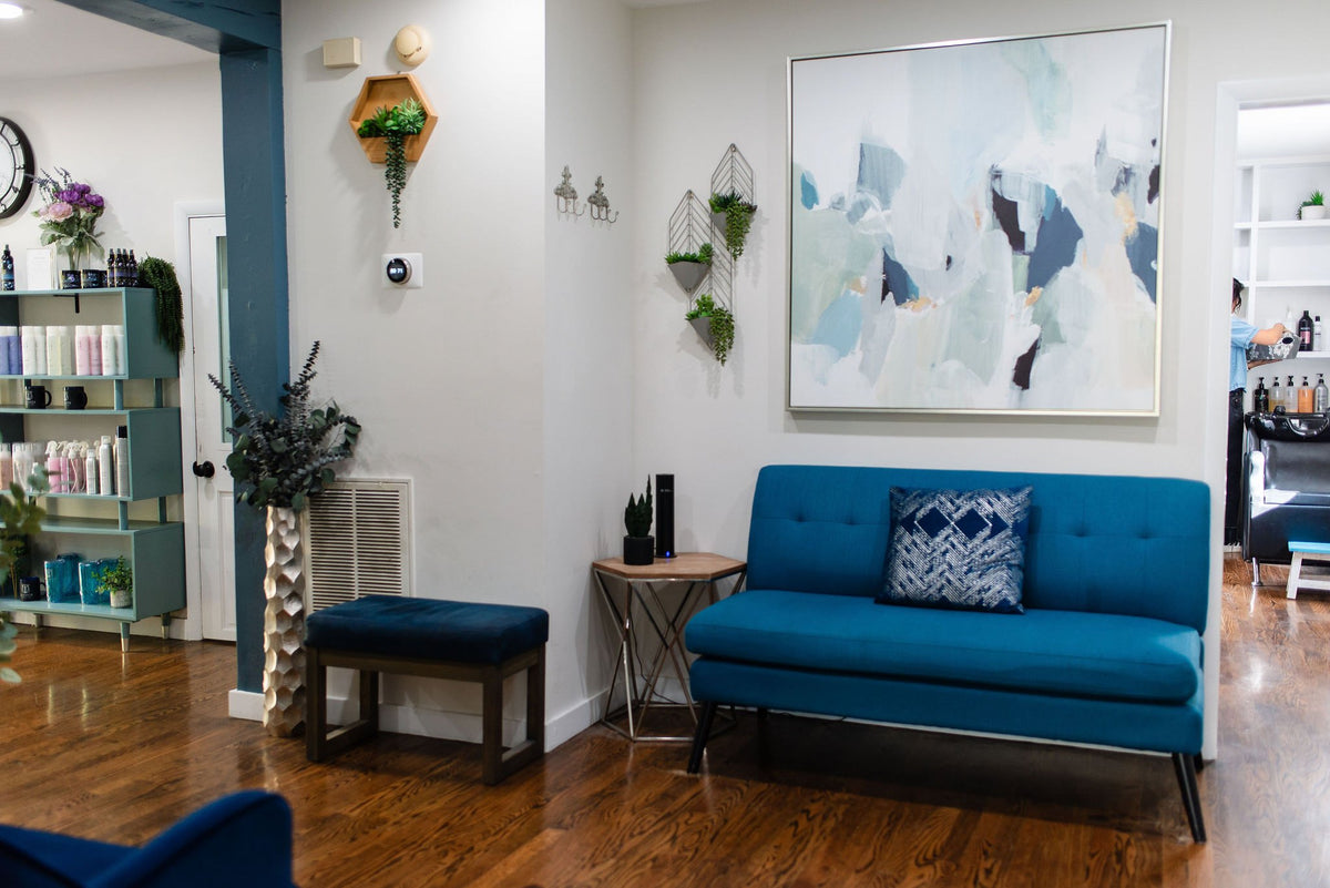 Waiting area with blue sofa and artwork at Elevate Salon + Spa, Charlottesville VA